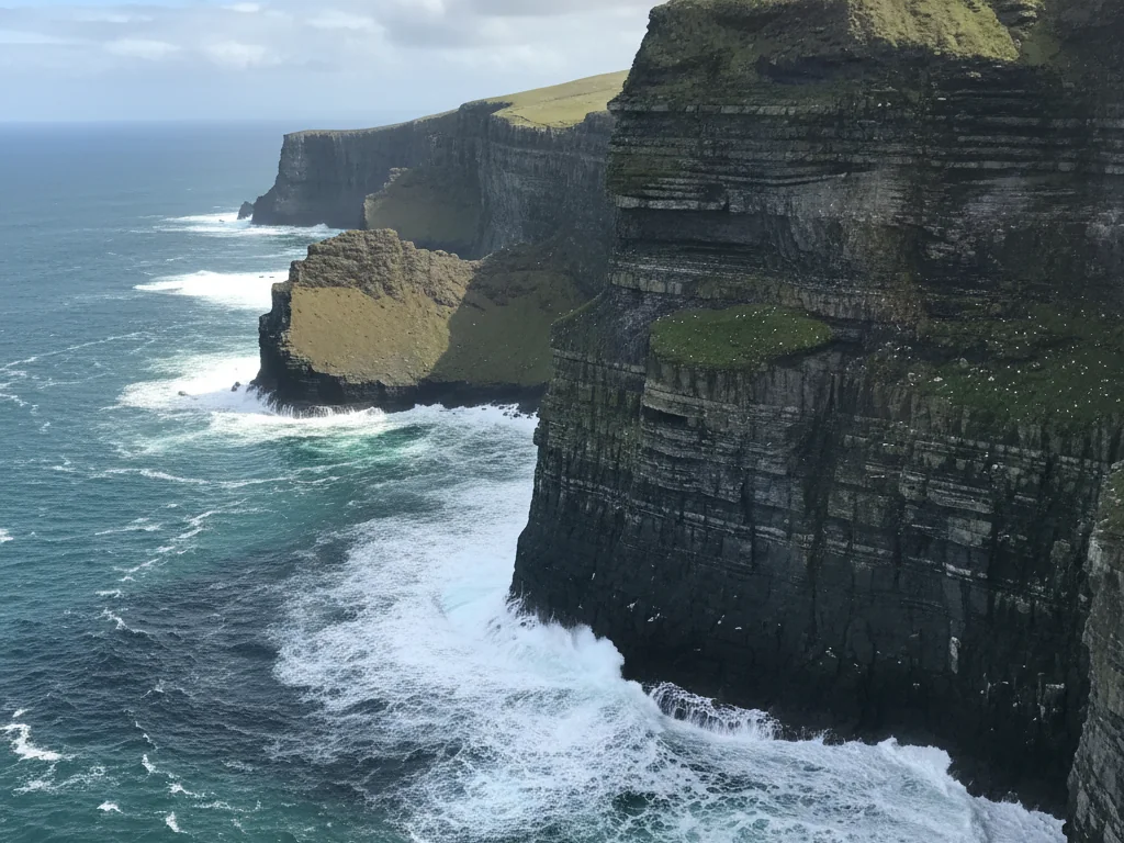 Cliffs of Moher's dramatic vertical rock faces plunging into crashing Atlantic Ocean waves below.