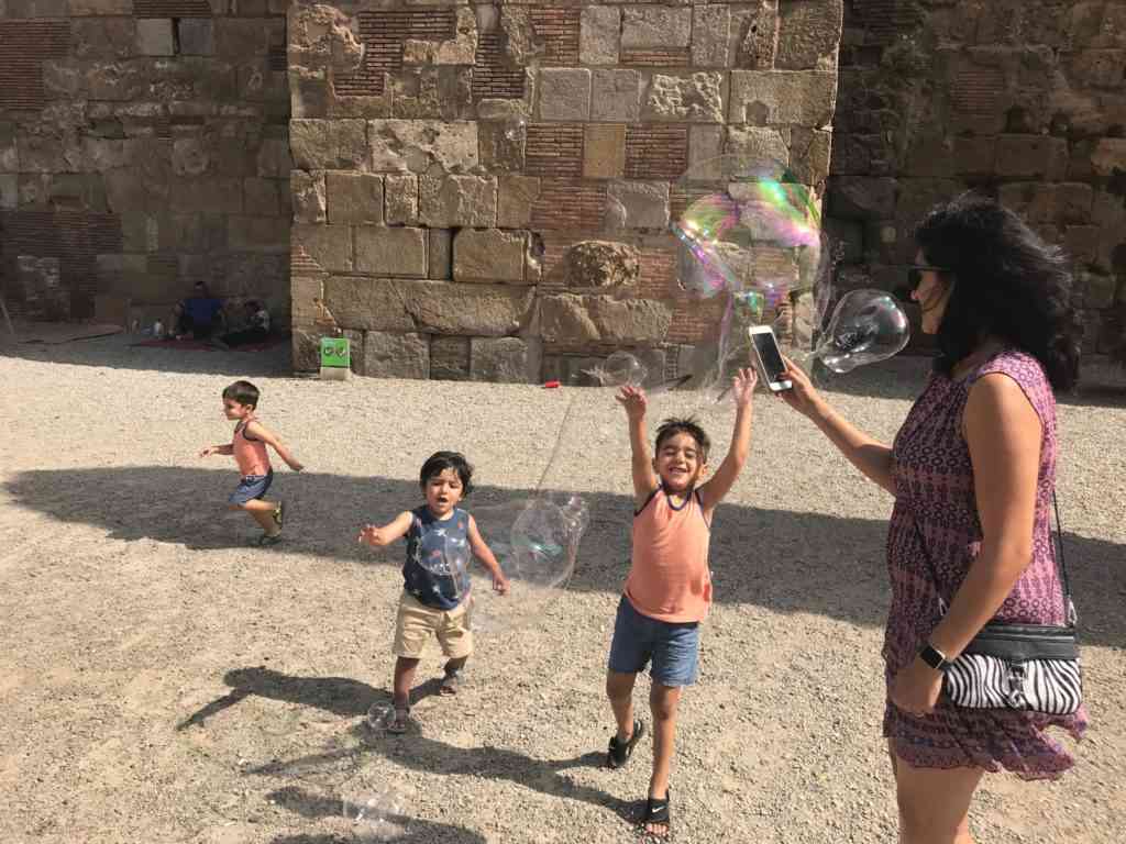 Cousins playing with the bubble man while Natasha looks on. In Gothic Quarter in Barcelona.