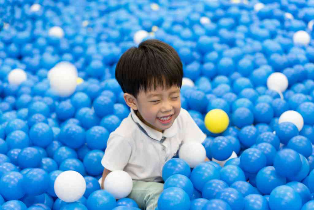 young boy in blue ball pit