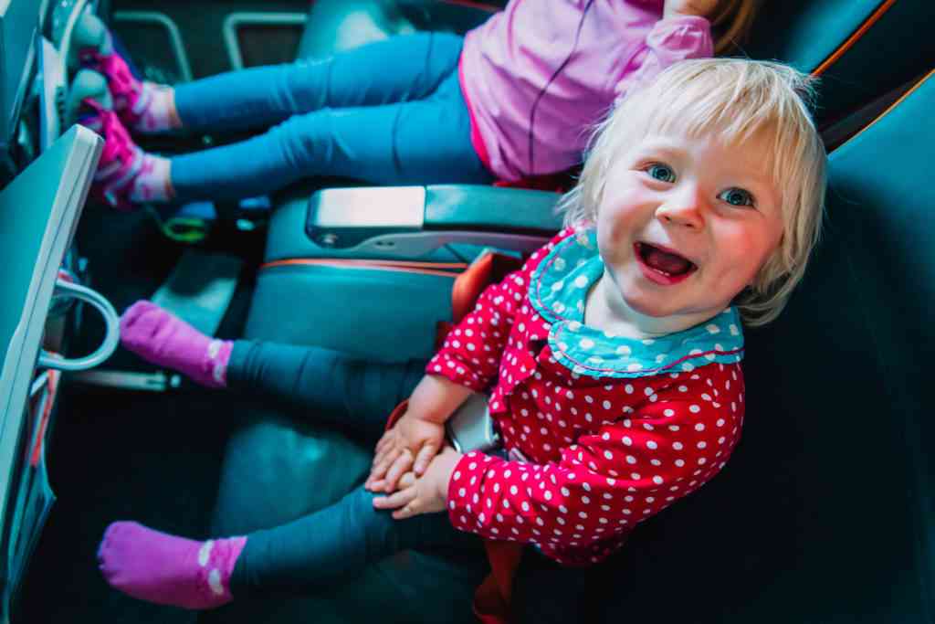 happy cute little baby girl with her sister travel by plane, family in flight